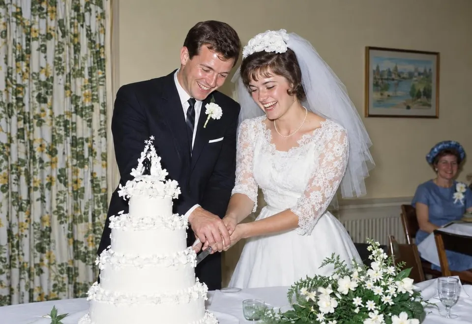 A 1960s couple cutting their wedding cake, the print folded into four and faded blue, restored